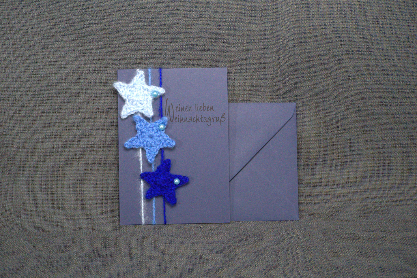 Handgefertigte Grußkarte in Blau mit gehäkelten Sternen aus 100% Wolle. Doppelkarte im DIN A6-Format mit passender Briefhülle in Blau – einzigartig & stilvoll.