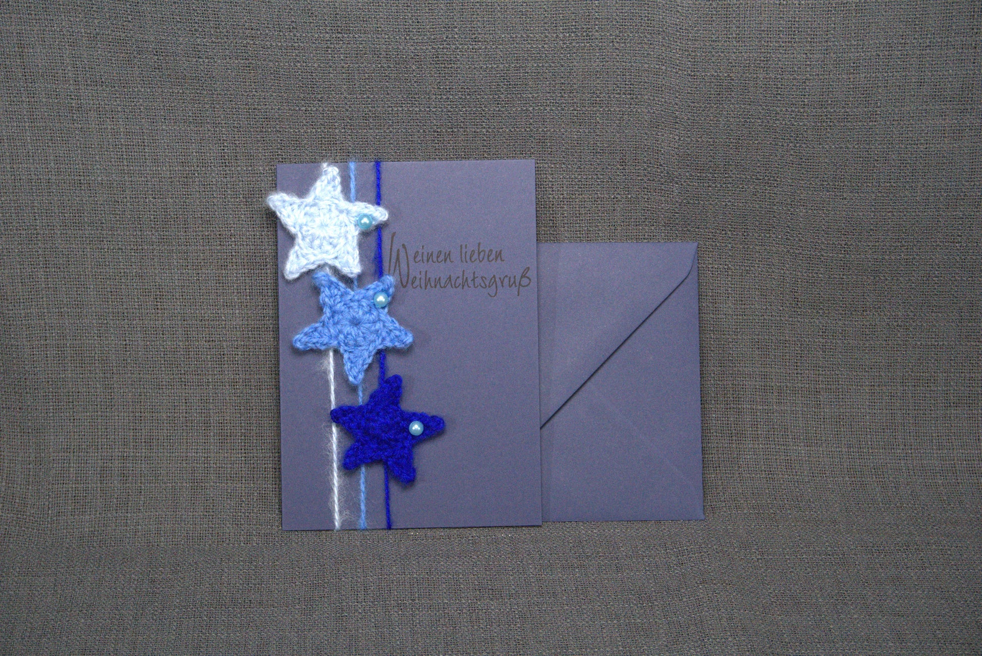 Handgefertigte Grußkarte in Blau mit gehäkelten Sternen aus 100% Wolle. Doppelkarte im DIN A6-Format mit passender Briefhülle in Blau – einzigartig & stilvoll.